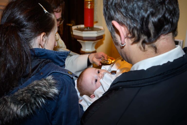 fotenie krstu v kosotle v Stupave, rodicia drzia male dieta ktore krsti farat svatenou vodou