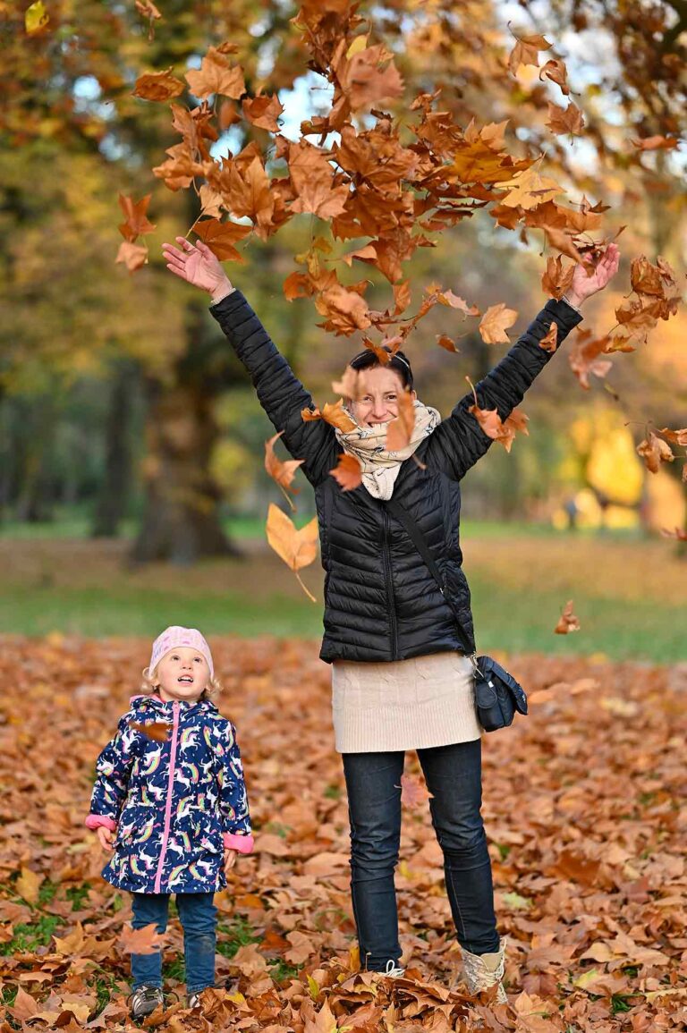 rodinne fotenie na jesen v parku v Stupave, matka a dcera vyhadzuju do vzuchu farebne listy